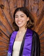 Female with shoulder length brown hair. She is wearing a grad gown and purple sash